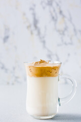 Quarantine trendy cuisine. Cup with dalgona coffee on a gray background. Vertical view