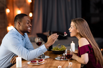 Happy Interracial Couple Having Romantic Moments At Dinner In Restaurant