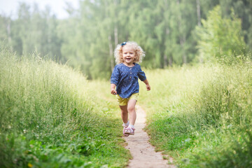 a girl with curly blonde hair walks in a meadow, a summer day