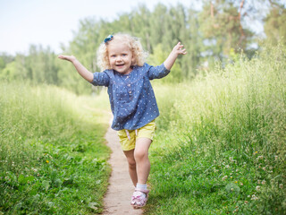 a girl with curly blonde hair walks in a meadow, a summer day