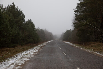 The track of a country paved forest road in late autumn in the first frost snow.