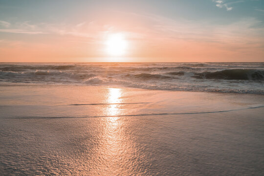 Sunset on the beach. Soft yellow-pink sunlight with beautiful sun reflections on golden sand © Hanna Tor