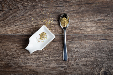 Metal spoon with seasoning dish on a wood floor