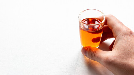 holds in hand a glass with alcohol on a white background with a place for text close-up