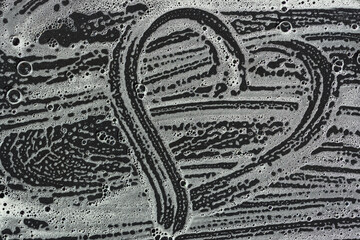 Fototapeta premium Background of a dark plate on which soapy water is blurred and bubbles. The foam forms a heart