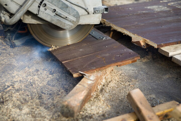 A worker cuts the wood with a petrol saw