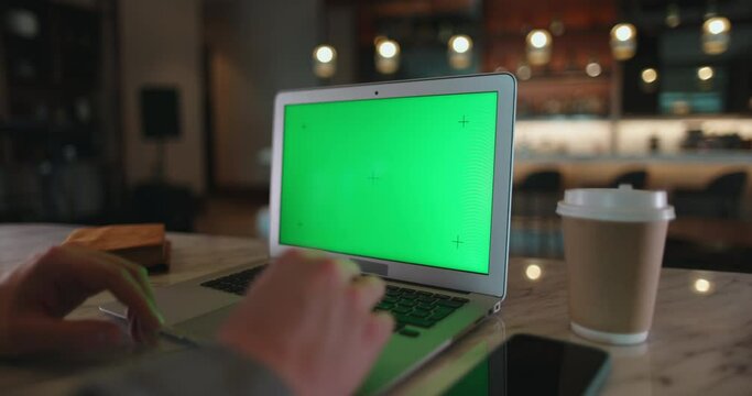 Close up shot of hands using laptop with chroma key green screen. Computer with mock up display at workplace in office cafeteria - technology concept 4k footage