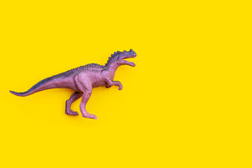 Plastic dinosaur toy on yellow background.