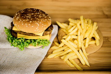  Cheeseburgers on a wooden background next to French fries, fast food