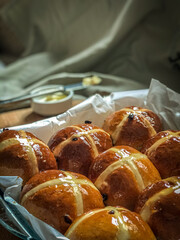 Homemade Hot Cross Buns. A spiced sweet bun made with fruit, marked with a cross on the top. Traditionally eaten on Good Friday in the United Kingdom. Knife with butter for tasting