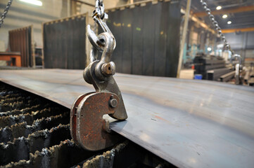 Lifting chains and hooks for loading sheet metal. Placing metal on a plasma cutting machine.