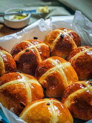 Homemade Hot Cross Buns. A spiced sweet bun made with fruit, marked with a cross on the top. Traditionally eaten on Good Friday in the United Kingdom. Knife with butter for tasting