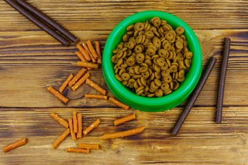 Dog delicacy food and feed in green plastic bowl on wooden background. Top view. Dog care concept
