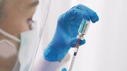 Close up hand of doctor or researcher with face mask holding and filling up a vaccine to syringe. Medical with face mask filling a syringe with vaccine. Covid19 coronavirus vaccine in a syringe. - Powered by Adobe