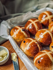 Homemade Hot Cross Buns. A spiced sweet bun made with fruit, marked with a cross on the top. Traditionally eaten on Good Friday in the United Kingdom. Knife with butter for tasting