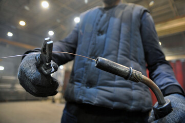 Welder's hands with pliers. Repair of welding equipment.
