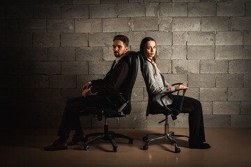 Bad relationship concept. Man and woman in disagreement. Young couple after a quarrel sitting on chairs back to back. Businessmen and partners did not share anything 