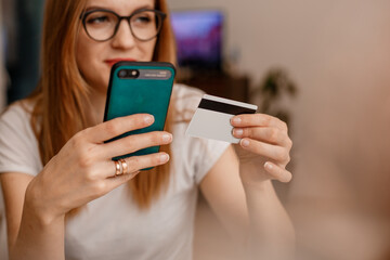 Using smartphone and credit card online shopping. Woman using mobile phone app playing game, shopping online, ordering delivery relax on sofa. A Woman shopping Online On Smartphone With A Debit Card.