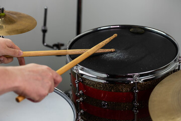 Professional drum set closeup. Man drummer with drumsticks playing drums and cymbals, on the live music rock concert or in recording studio   