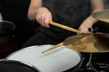 Professional drum set closeup. Man drummer with drumsticks playing drums and cymbals, on the live music rock concert or in recording studio   