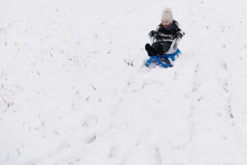 Cute cute boy in a sled in the snow, active lifestyle, winter, family