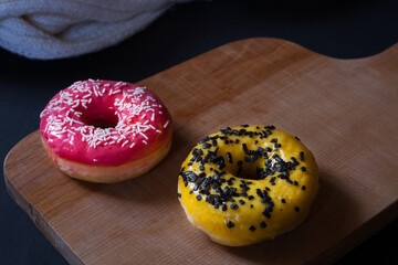 Delicious red and yellow donut on a wooden background. Close-up. 