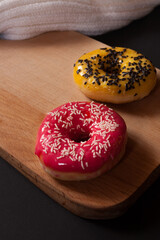Delicious red and yellow donut on a wooden background. Close-up. 