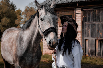 Fototapeta premium Cowboy girl in a cowboy hat with horse 