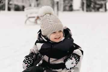 Cute cute boy in a sled in the snow, active lifestyle, winter, family