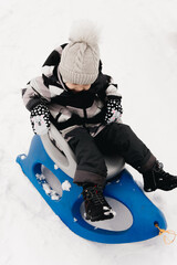 Fototapeta na wymiar Cute cute boy in a sled in the snow, active lifestyle, winter, family