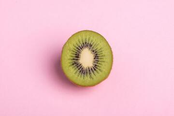 Close-up of a kiwi sliced on pastel pink background.