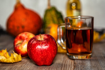 Glass of apple cider with apples, pumpkins and persimmon on wooden table