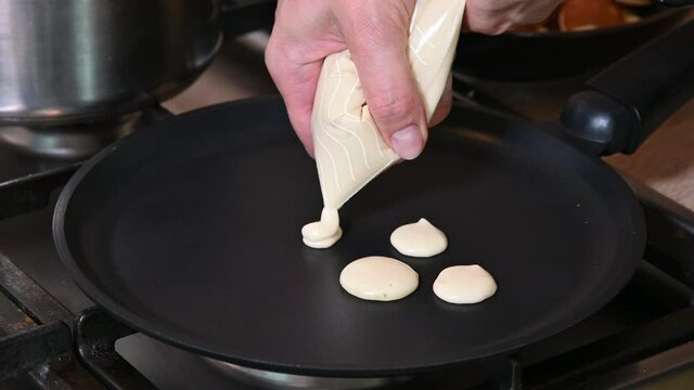 Chef pouring dough is into pan for cooking mini pancakes for breakfast. 4k video