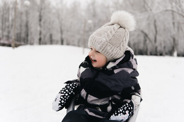 Cute cute boy in a sled in the snow, active lifestyle, winter, family