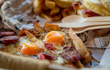 Delicious brunch made of eggs,potatoes,sausages and tomatoes, served on wooden tray. 