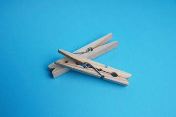 Wooden clothespin isolated on a blue background. The clothespin is a fastener used to dry clothes.