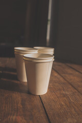 disposable cups made of white kraft paper stand on a wooden table