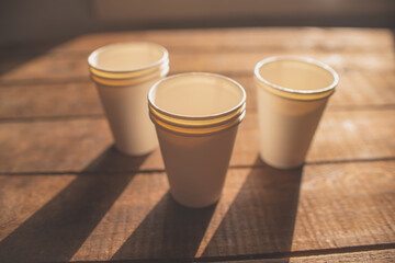 disposable cups made of white kraft paper stand on a wooden table