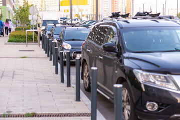 Car parking poles. Cars are parked parallel to the houses.
