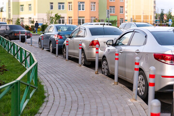 Car parking poles. Cars are parked parallel to the houses.