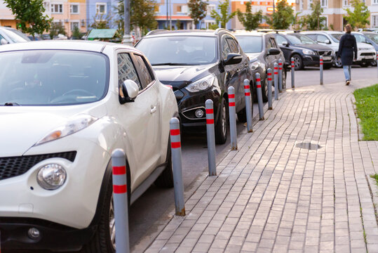 Car parking poles. Cars are parked parallel to the houses.