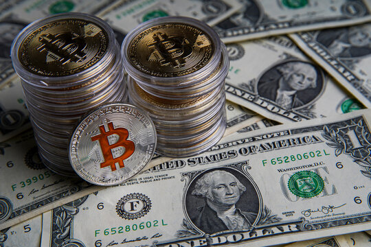 Pile of US dollar cash. Next to it are a number of gold bitcoins and a silver digital cryptocurrency coin. Bank image and commercial photo background. 