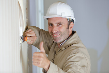 man stripping wallpaper making thumbs-up gesture