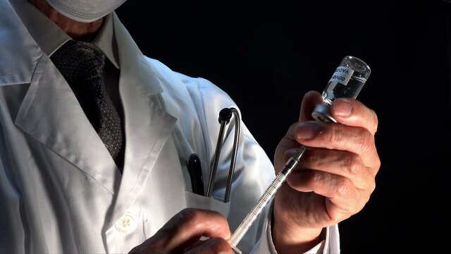 バイアル瓶から注射器に薬を吸引する医師。ワクチン接種イメージ