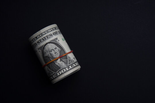 Money rolls wrapped with red rubber band isolated on black background. One Dollar is a portrait of the late George Washington, the first president of the United States. Bank image and commercial photo