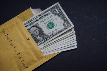 The concept of corruption and bribery. Envelope full of american dollar banknotes. They bribe or blackmail. translation: open here