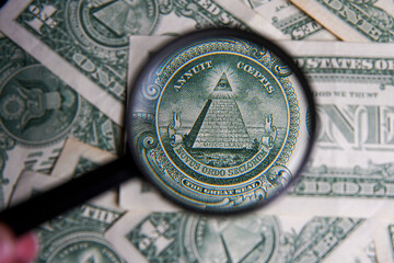 US dollar viewed through a magnifying glass, close up detail of the pyramid. Masonic symbols. Bricklayer signs on the dollar: All-seeing eye, pyramid. Bank image and commercial photo background.