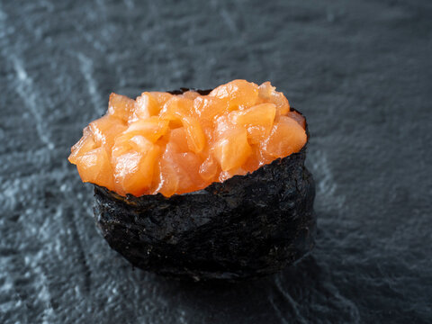 minced salmon guncan on a black textured surface. Close-up side view. Japanese cuisine