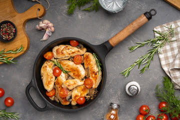 Grilled chicken breast or fillet with tomato on iron pan. Top view.