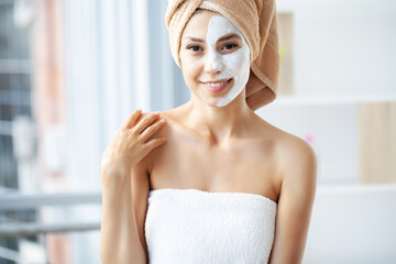 Attractive funny woman with a clay mask on her face.